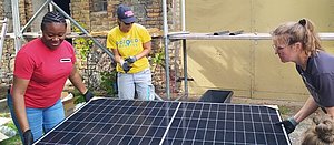 FLINTA heben ein Solarmodul und transportieren es